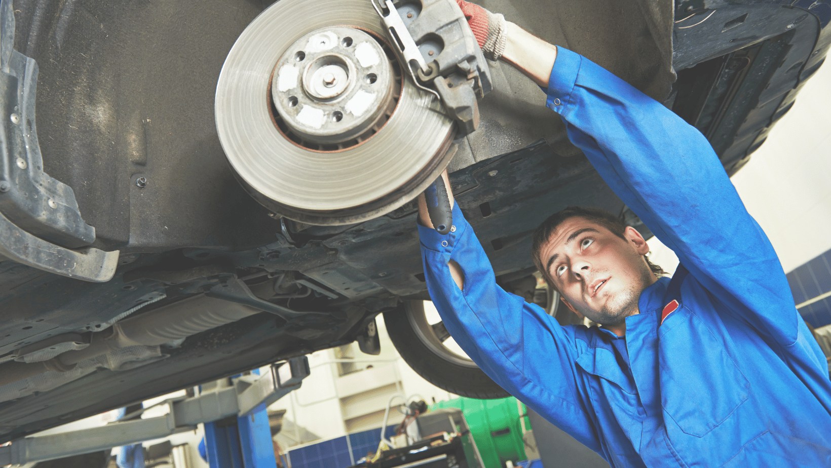 technician working on wheels while car is on a lift