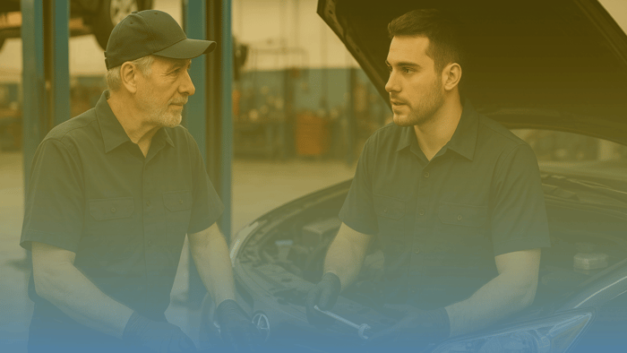 two technicians  talking in front of a car in a shop