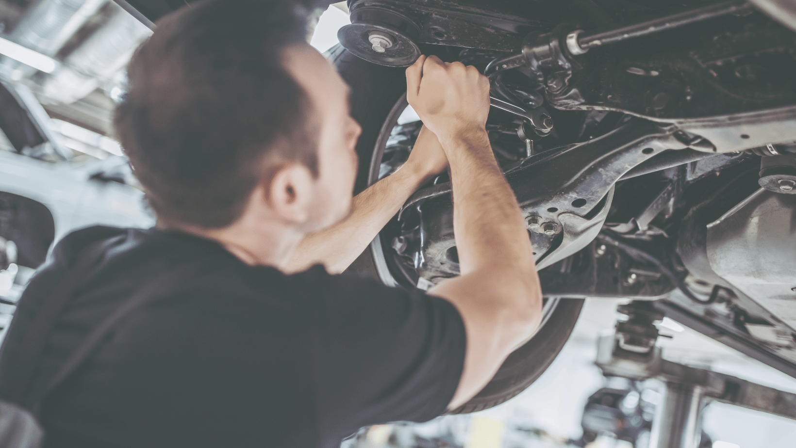 technician working on the underside of a car