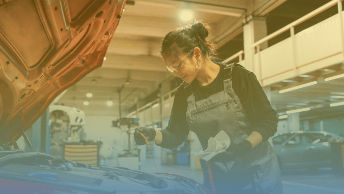 technician checking oil on a car in an auto repair shop