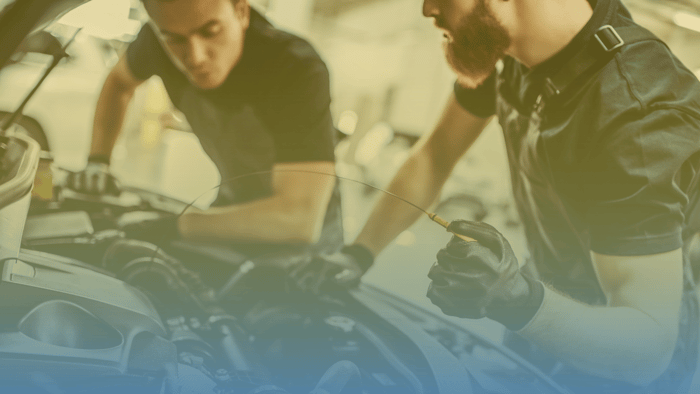 two technicians working under the hood of a car 