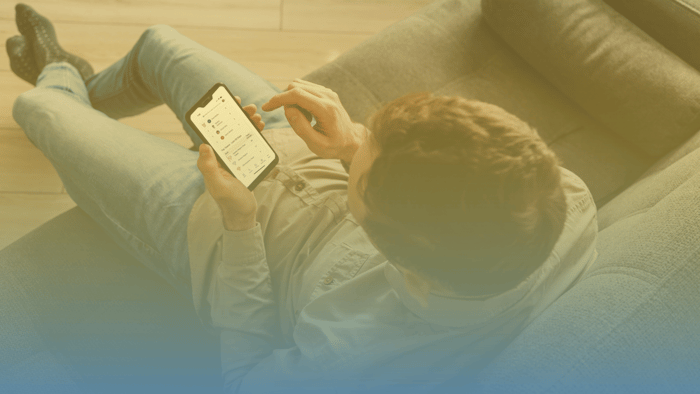 man on couch holding a cell phone