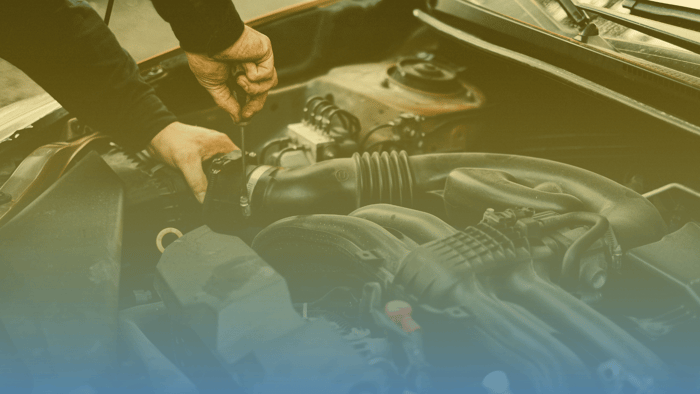 technician using screwdriver under car hood