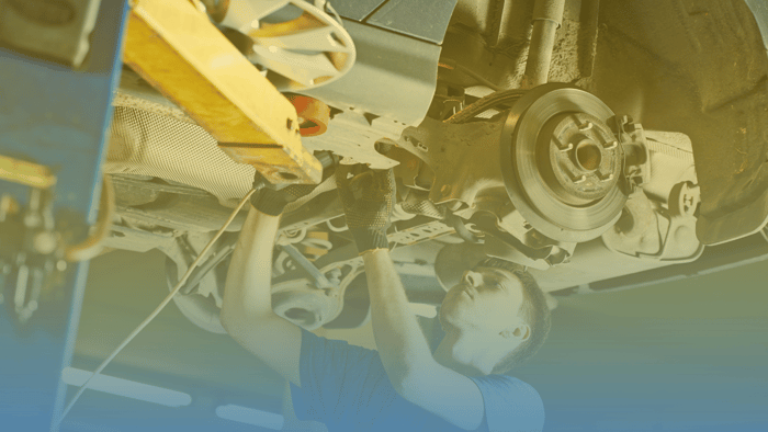 technician working under a vehicle on a lift