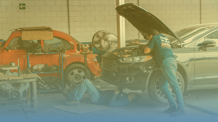 two technicians working on a car in a shop